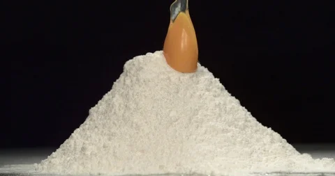 Egg falling onto flour in slow motion Stock Footage 97809624