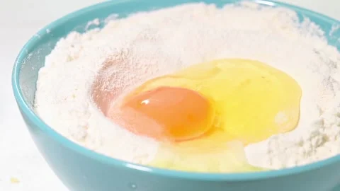 Egg falling into flour slow motion shot Stock Footage 148823874