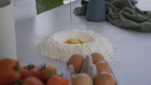 Egg falling into mound of flour in kitchen preparation for dough Stock Footage 255722733