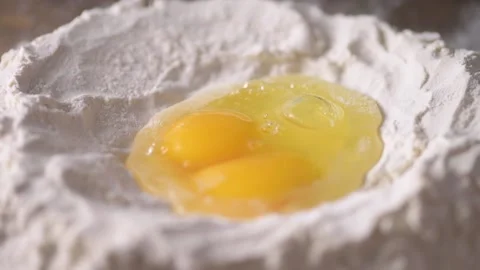 Egg falling into pool of egg and flour in slow motion 120 fps Stock Footage 171484779