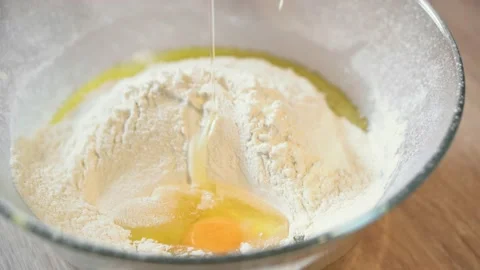 Egg falls into the bowl with flour for banana cake dough, close-up. Stock Footage 166562353