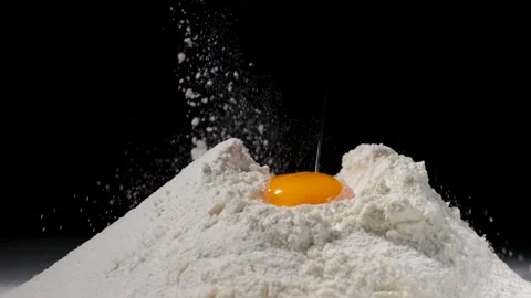 Egg falls into the flour on black background. Slow motion video Stock Footage 146056143