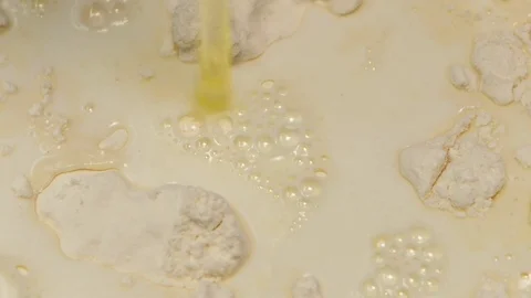 Egg falls into flour with milk in slow motion, closeup Stock Footage 76168308