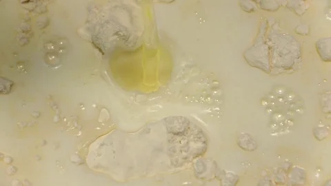 Egg falls into flour with milk in slow motion. Closeup Stock Footage 76168740