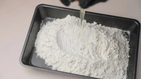 The egg falls into the flour. With a slow motion, the egg falls into a baking Stock Footage 165805478
