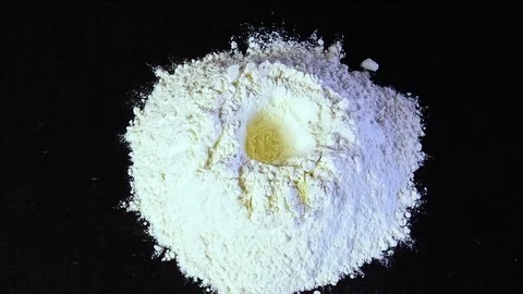The egg falls into the flour slowly Видео 75005772