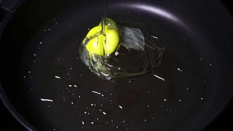 Egg falls on a frying pan super slow mo Video stock 72373846