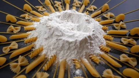 Egg falls on a pile of flour and Table with different type of pasta Stock Footage 119720950
