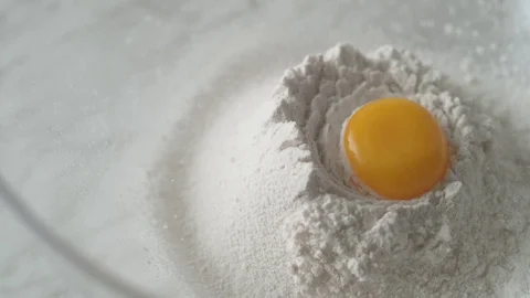 Egg falls on a pile of flour. Slow Motion. Video stock 79477097