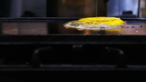 Egg fried falling on a black griddle and cooked with steam and melted yolk S Stock Footage 246552886