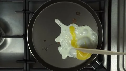 The egg is fried in a frying pan. The yolk is broken with a spatula Stock Footage 150327532