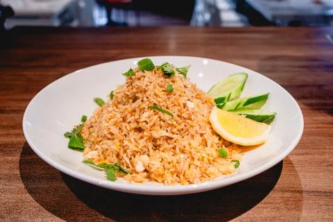 Egg fried rice with a side of cucumber slices and a lime wedge. Stock Photos