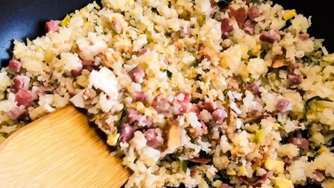 Egg fried rice with vegetables and meat during preparation on black iron pan. Stock Footage 304854650