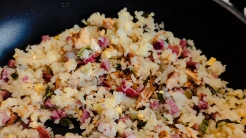 Egg fried rice with vegetables and meat during preparation on black iron pan. Stock Footage 304854720