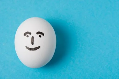 An egg with a happy, joyful face. Isolate on a blue background. Fotos Stock