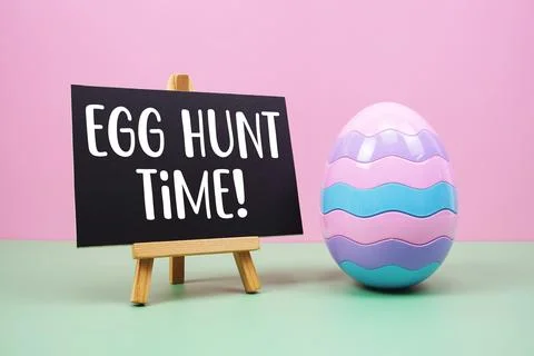 Egg Hunt Time! text with egg on pink and green background Stock Photos
