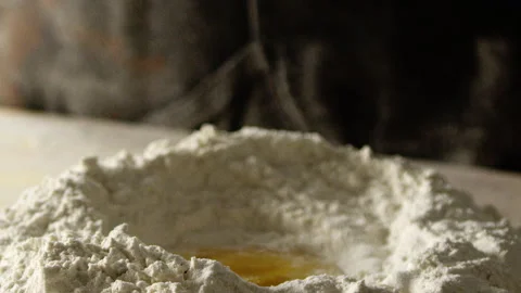 Egg in middle of flour heap on counter surface with apron in background Stock Footage 274689231