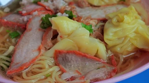 Egg noodle soup, topping with slice red roasted pork and wontons. Stock Footage 310249396