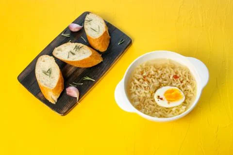 Egg noodles on a yellow background, bread and garlic on a wooden board. Stock Photos