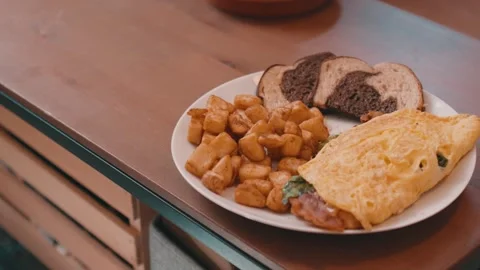 Egg Omelet, Homefries and Rye Toast on a White Plate on a wooden table in 4k Stock Footage 245452742