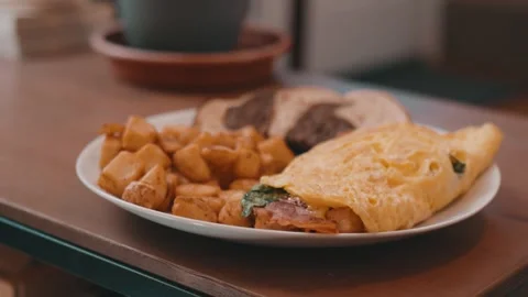 Egg Omelet, Homefries and Rye Toast on a White Plate on a wooden table in 4k Stock Footage 245452800