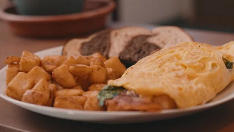 Egg Omelet, Homefries and Rye Toast on a White Plate on a wooden table in 4k Stock Footage 245452971