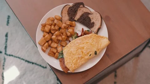 Egg Omelet, Homefries and Rye Toast on a White Plate on a wooden table in 4k Stock Footage 245452977