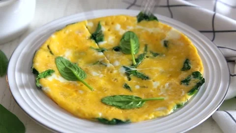 Egg omelet with spinach and cheese on a white plate Stock Footage 147732324