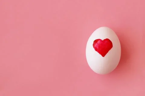 Egg with painted watercolor heart for Easter on pink background Stock Photos