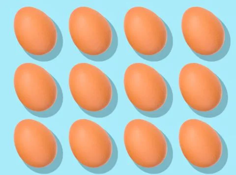 Egg pattern: raw chicken eggs on a purple background, one broken egg. Top vie Stock Photos