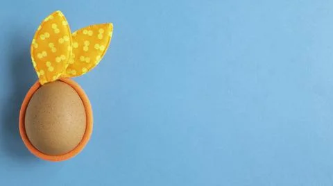 Egg with rabbit ears on a blue background. Minimal Easter concept. Stock Photos