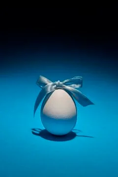 Egg with ribbon as a symbol of Easter on a light blue background Stock Photos