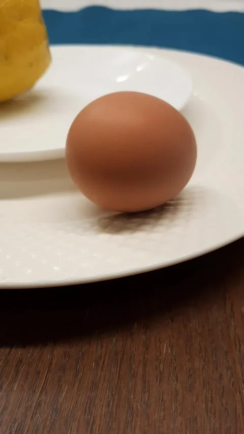 Egg rocking on plate next to lemon Stock Footage 328452136