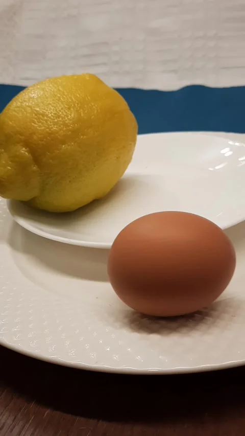 Egg rocking on plate next to lemon Stock Footage 328452877