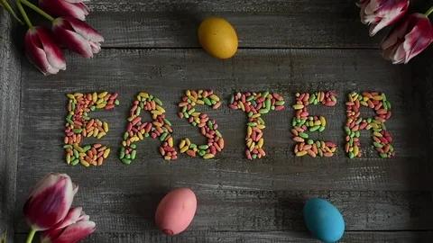 Egg is rolling on easter sign, decorated with eggs and tulips Video stock 73379813