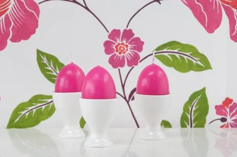 Egg shape candle in egg cup against floral pattern Foto stock