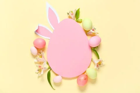 Egg-shaped blank card with paper bunny ears, Easter eggs and alstroemeria flo Stock Photos