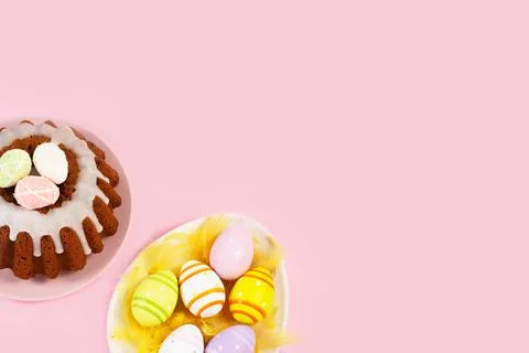 Egg-shaped plate with easter eggs and Glazed easter cake on pink background. Stock Photos