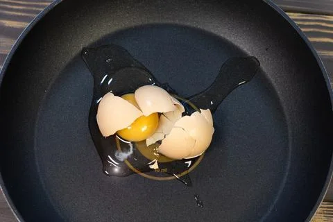 Egg with shell broken on frying pan. Close up, failed cooking. Stock Photos