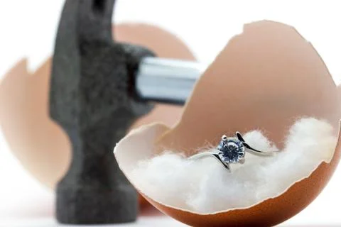 The egg shell is broken by a hammer and fake diamond ring in the egg shell. Stock Photos