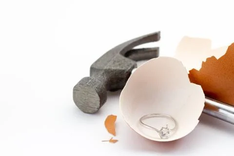 The egg shell is broken by a hammer and fake diamond ring in the egg shell. Stock Photos