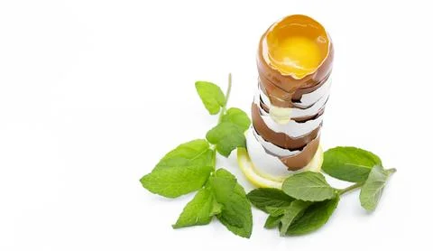 Egg shells stacked with a cracked egg with yolk and white spilling out on w.. Stock Photos