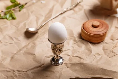 Egg in silver egg cup with spoon and salt pot on paper background. Lunch Stock Photos