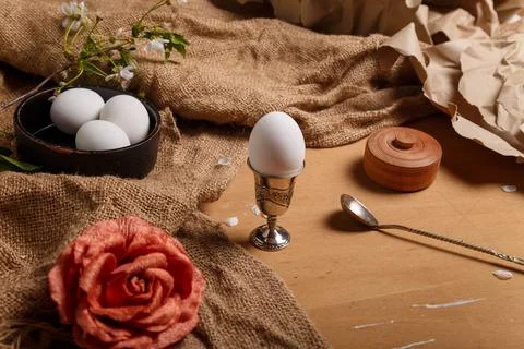 Egg in silver egg cup with spoon salt pot, cherry blossom. fabric rose flower Foto stock