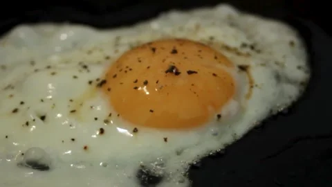 The egg is sizzing in a pan, and boiling oil is boiling around. Close up Stock Footage 314978889