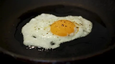 The egg is sizzing in a pan, and boiling oil is boiling around. Organic camera Stock Footage 314979082