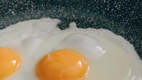 The egg sizzles as it hits the hot pan, the clear liquid slowly turning white Stock Footage 308798434