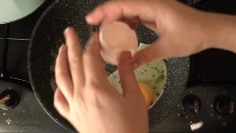 The egg is smashed on a frying pan on a dirty stove, with a whole yolk Stock Footage 323017118