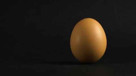 The egg spin by hand. A brown egg spinning on a dark background. Stock Footage 103239117