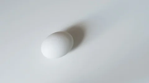 Egg spinning.Chicken egg spinning on white background top view. Egg spinning and Stock-Footage 107960084